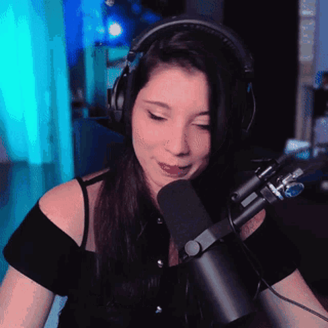 a woman wearing headphones and a microphone looks at the camera