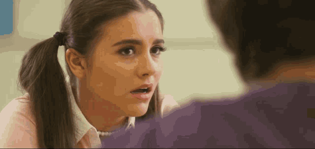 a girl with pigtails is talking to a man and making a funny face