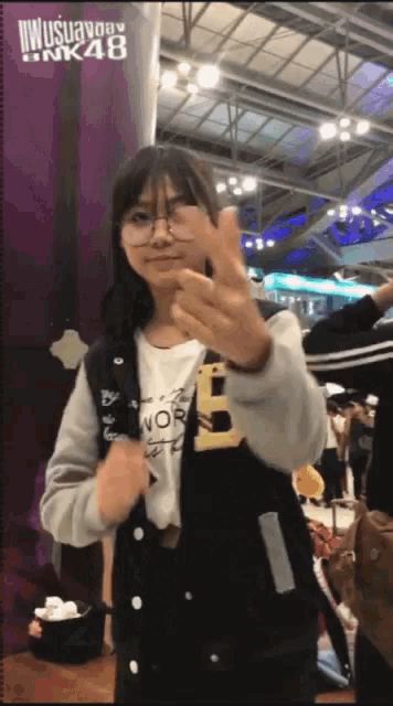 a girl giving a peace sign in front of a sign that says " nk48 "