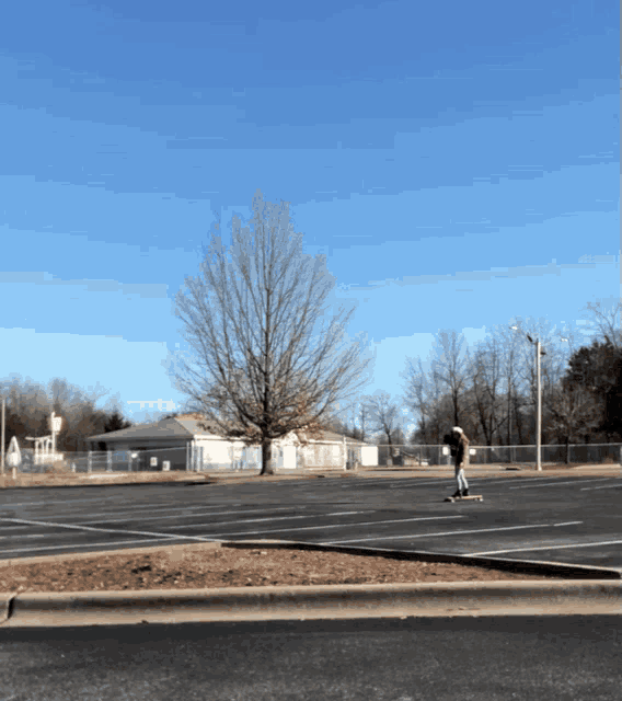 a person riding a skateboard in a parking lot with a water tower in the background