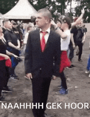 a man in a suit and tie stands in front of a crowd with the words naahhhh gek hoor written below him