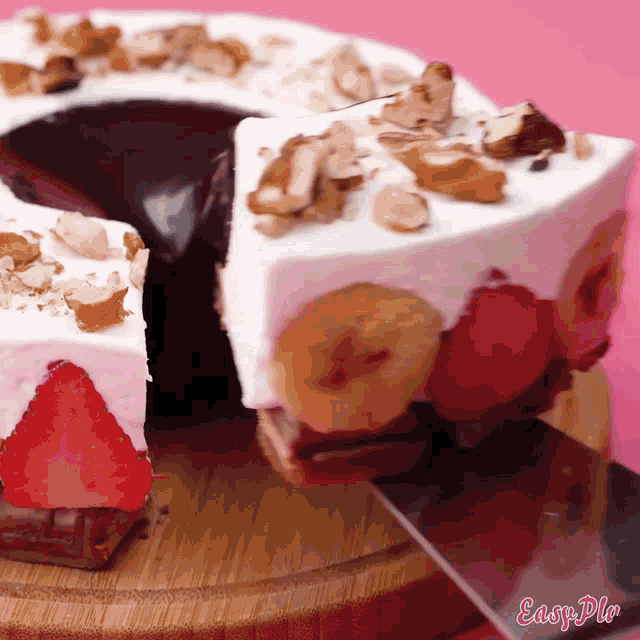 a cake with strawberries and bananas on it is on a wooden cutting board with easy pin written on it
