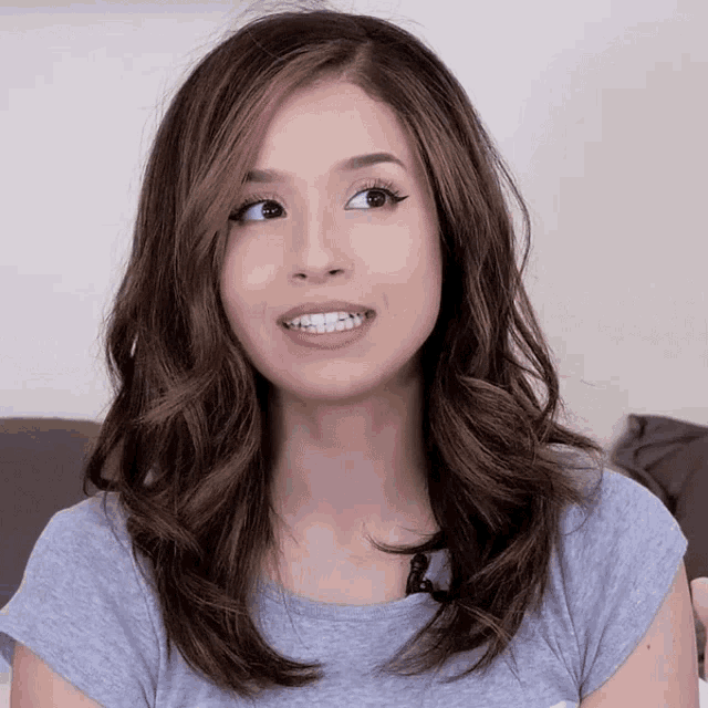 a woman with long brown hair is wearing a grey t-shirt
