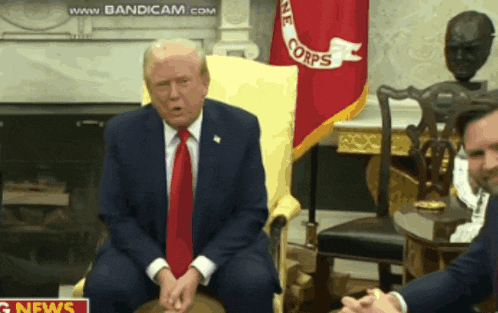 a man in a suit and tie is sitting in front of a flag that says corps
