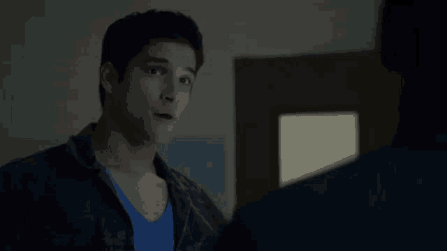 a man in a blue shirt is standing next to another man in a room .