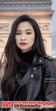 a woman wearing a black leather jacket is standing in front of a building .