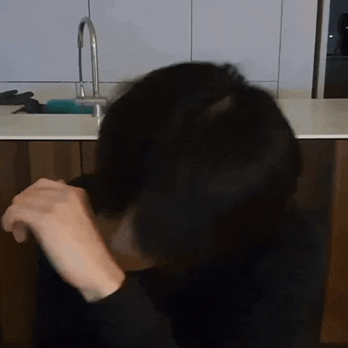 a person is sitting in front of a sink with a faucet in the background .