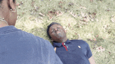 a man wearing a polo shirt is laying on the grass