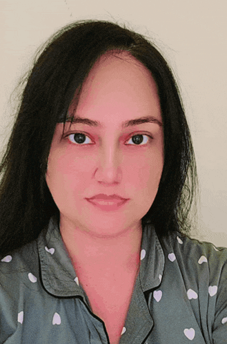 a woman wearing a pajama top with hearts on it looks at the camera