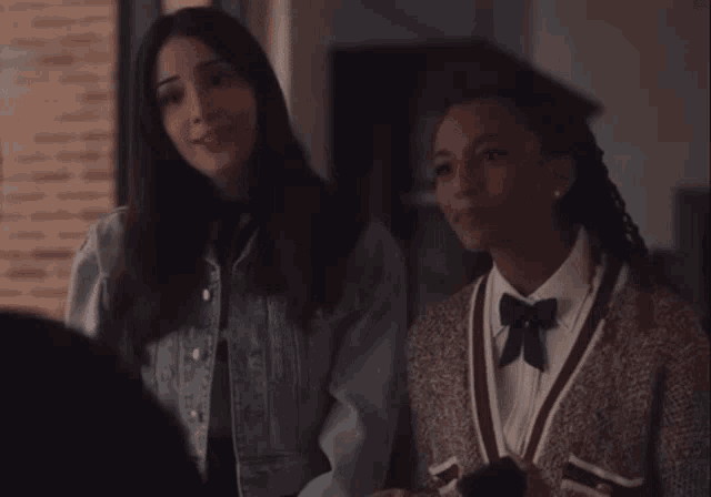two women are standing next to each other in a dark room and smiling