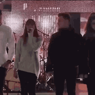 a group of people are standing on a stage in front of a microphone .