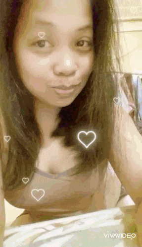 a woman is taking a selfie with hearts around her face and breasts .