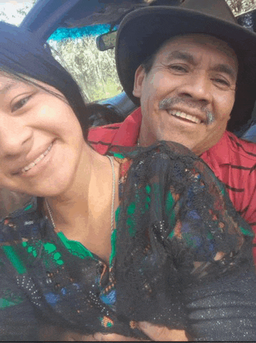 a man and a woman are posing for a picture and the man is wearing a hat