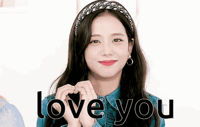 a woman is making a heart shape with her hands and the words love you are behind her