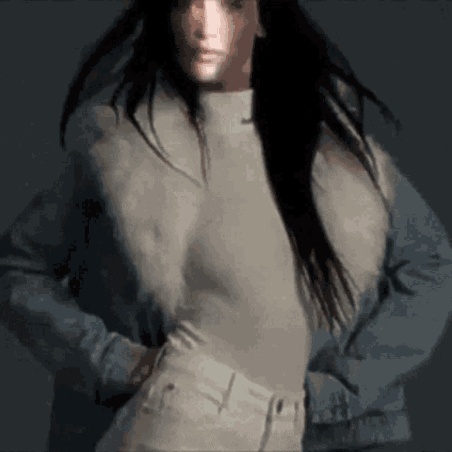 a woman with long hair is wearing a denim jacket and a white top