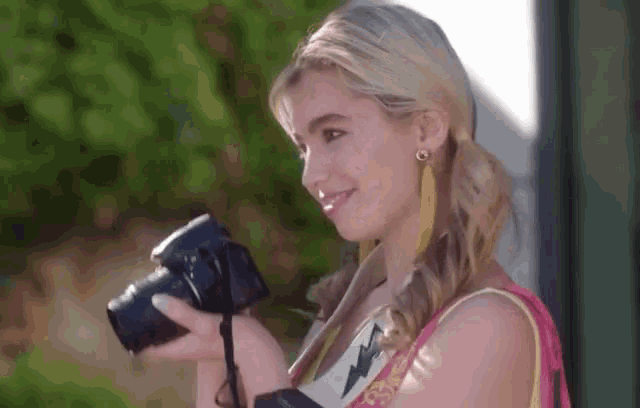 a woman is holding a camera in her right hand