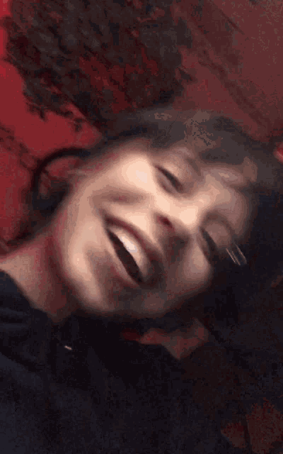 a close up of a person 's face laughing with a red background