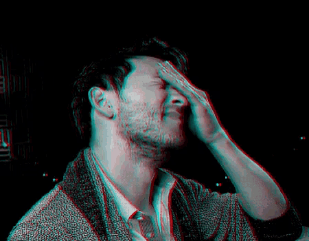 a man with a beard is blowing his nose in a dark room