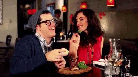 a man and a woman are sitting at a table eating
