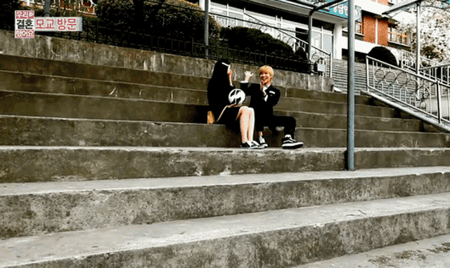 a man and a woman are sitting on a set of stairs with a sign that says ' seoul ' on it