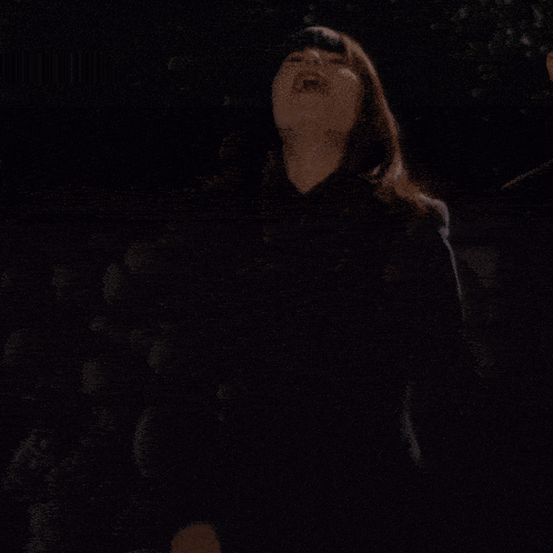 a woman in a black dress is laughing with her mouth wide open