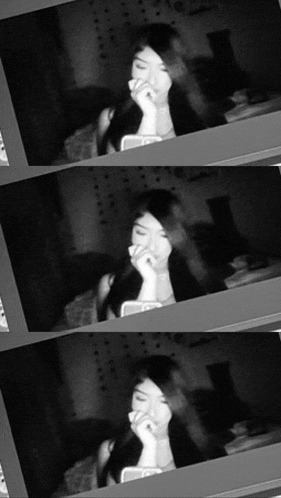 a black and white photo of a woman looking at a cell phone