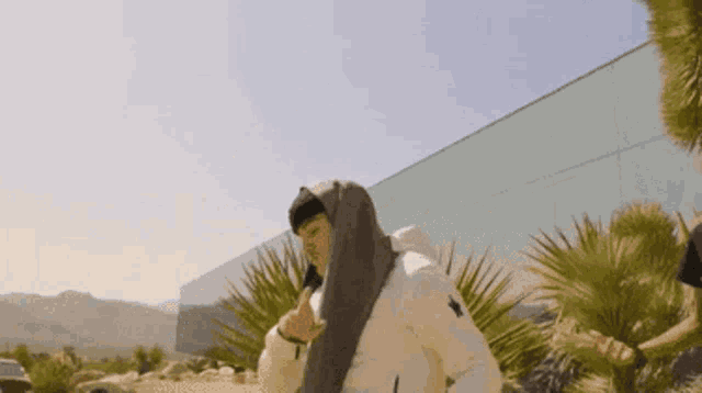 a man in a white jacket is standing in front of a building .