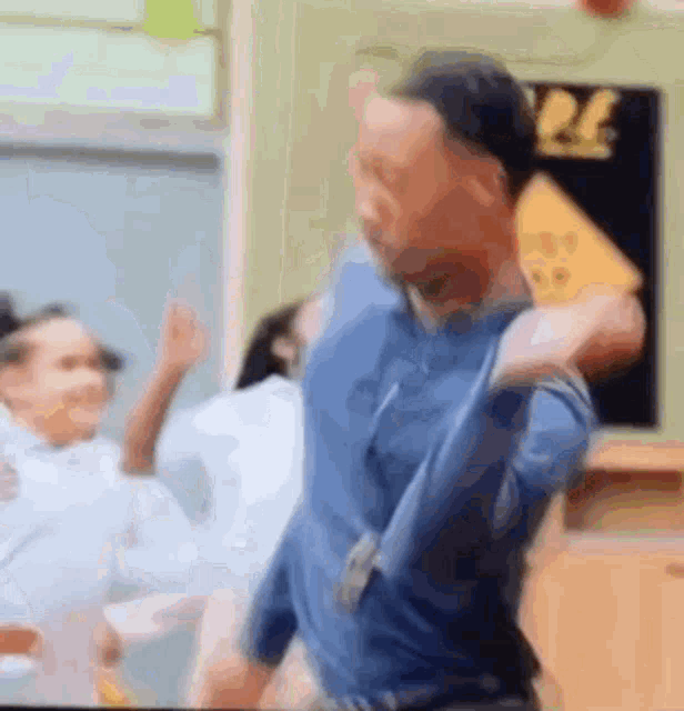a man in a blue shirt is dancing in front of a group of people .