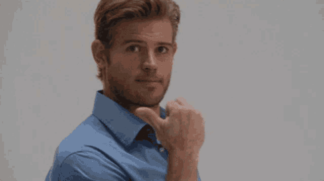 a man in a blue shirt is giving the thumbs up sign