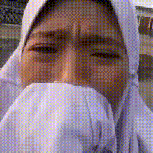 a woman wearing a white hijab is covering her face with a white cloth .