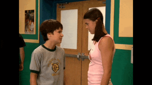 a boy and a girl are standing next to each other and the girl is wearing a shirt that says wolf pack on it
