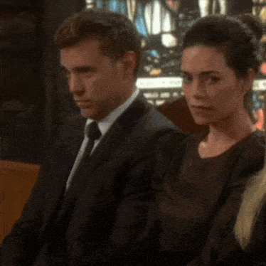 a man in a suit and tie sits next to a woman in a brown dress