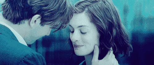 a man and a woman are touching each other 's faces and looking into each other 's eyes .