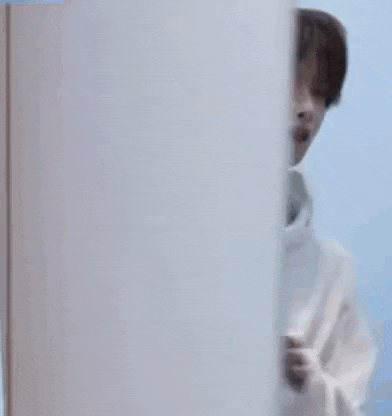 a young man in a white hoodie with a picture of a dog on it is standing in front of a door .