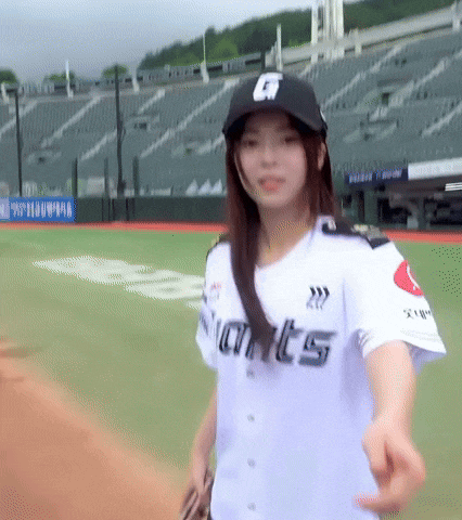 a woman wearing a giants jersey is standing on a baseball field