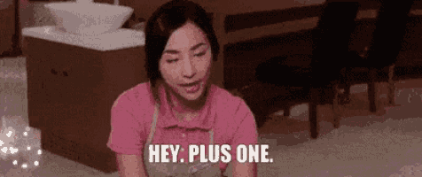 a woman in a pink shirt and apron is sitting on the floor and saying `` hey , plus one . ''