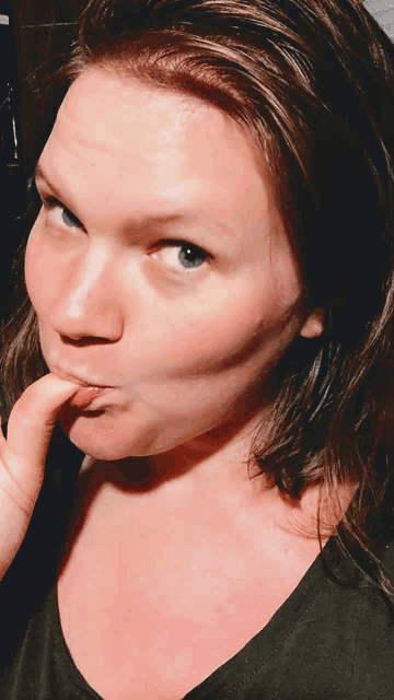 a close up of a woman making a funny face with her finger in her mouth