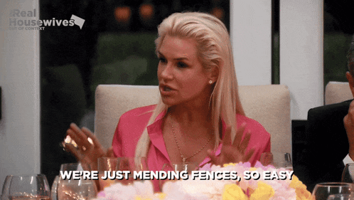a woman sitting at a table with a sign that says real housewives in the background