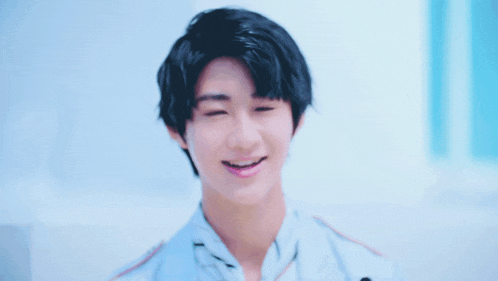 a young boy with black hair and a white shirt smiles for the camera