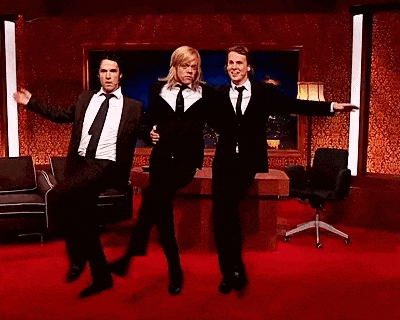a group of men in suits and ties are dancing in a room .