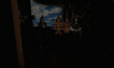 a group of people in party hats are standing in a room with balloons