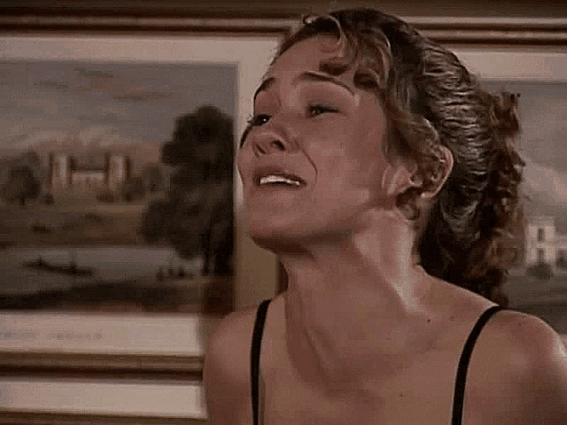 a woman in a black bra is standing in front of a framed painting .