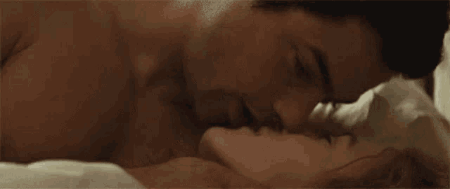 a man and a woman are kissing in a bed .