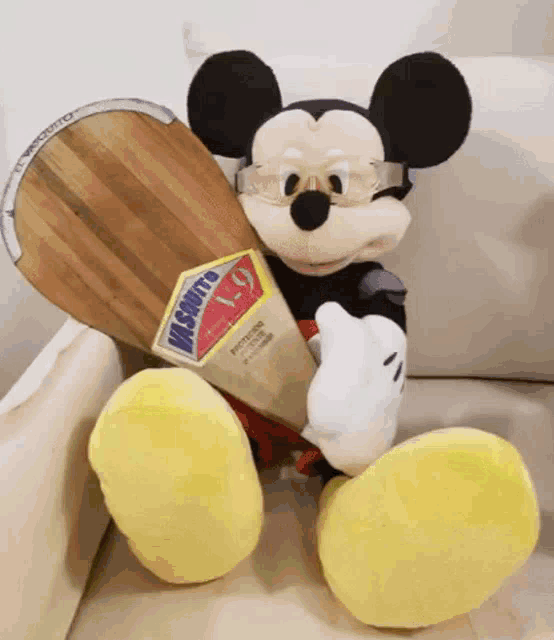 a stuffed mickey mouse is sitting on a couch holding a board that says vasquito