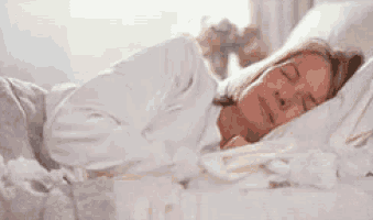 a woman is sleeping in a bed with white sheets .