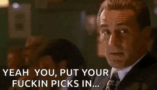 a man in a suit and tie is smoking a cigarette while sitting at a table .