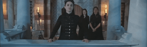 a woman in a black dress is standing in front of a group of women