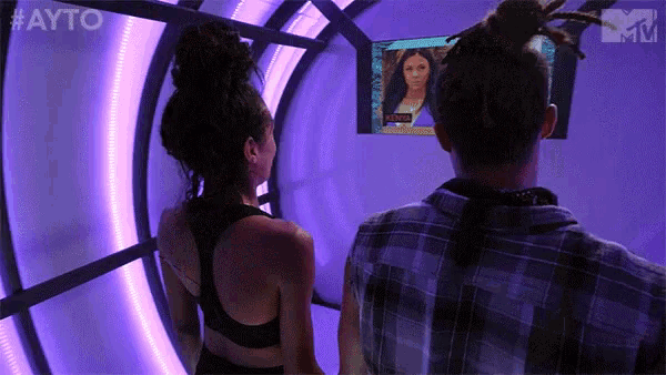 a man and a woman are standing in front of a screen .