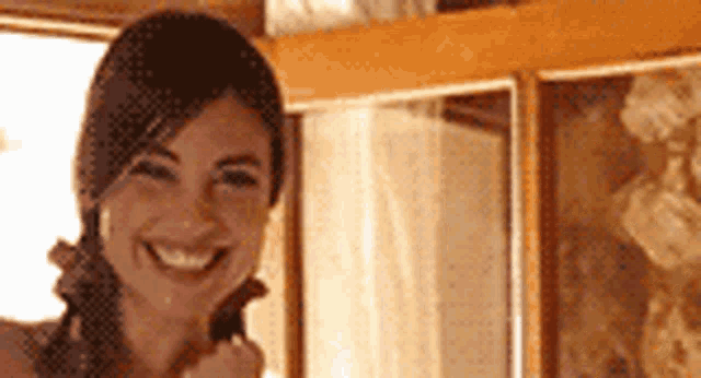 a woman is smiling while standing in front of a window .