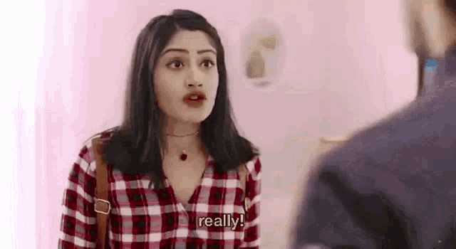 a woman in a plaid shirt is standing next to a man in a room .